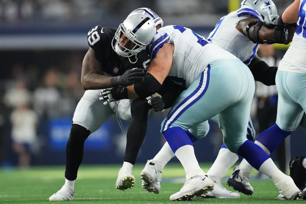 Jogador do Dallas Cowboys aplica tackle em jogador do Las Vegas Raiders durante partida da NFL.